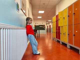 Young girl in red sweater leaning against a wall in a school hallway, surrounded by colorful lockers, showcasing a vibrant educational environment with a sense of curiosity and exploration