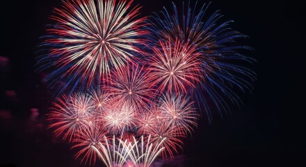 Vibrant firework display bursting with red, white, and blue against a dark sky