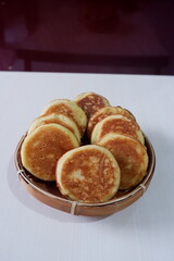 Authentic kue kamir, a beloved snack from Pemalang, Indonesia, displayed in a traditional bamboo basket. These soft, round cakes are known for their fragrant aroma and sweet, comforting flavor. 