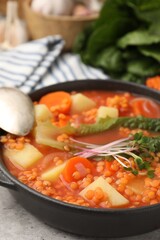 Tasty lentil soup served on grey table, closeup