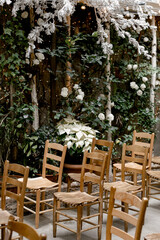 Charming outdoor setup with wooden chairs in a garden adorned with greenery and white flowers for a special gathering