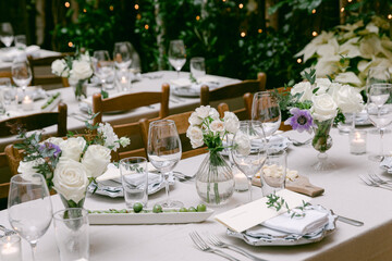 Elegant dining setup with white flowers and greenery for an outdoor event in a garden setting