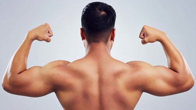 Man flexing muscles rear view against a light background