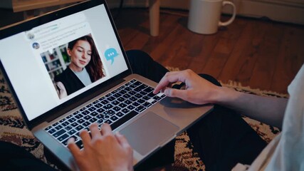 Person is typing on a laptop keyboard, using a messaging application for online communication and social networking while sitting on the floor at home - Powered by Adobe