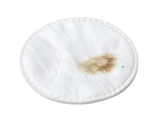 Used white cotton pad with brown cosmetic makeup stain and small specks on isolated background