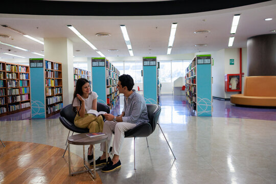 Two university students reading in a cozy library setting, showcasing learning, focus, and collaboration for education and study-themed visuals.
