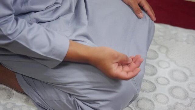 A close-up of a person reciting dhikr with their hands, counting on their fingers. A symbol of spiritual practice and devotion. Islam. A Muslim. 
