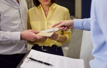 Cropped view of young couple discussing ceramic tile samples with consultant in showroom office....