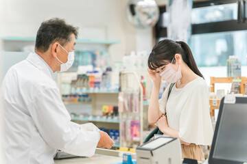 Fototapeta premium A pharmacist gives advice to a woman who is feeling unwell at a hospital/pharmacy 