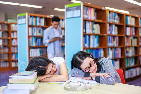 Two university students fall asleep in the library, capturing a real study break moment with tired, relaxed, and relatable campus energy.