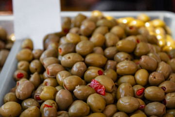 Green olives with red pimentos displayed in bulk market container