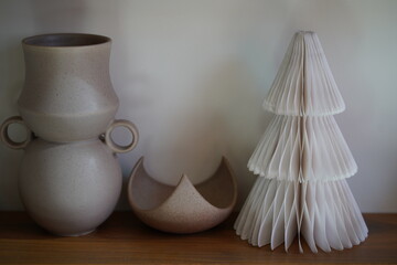 Elegant ceramic vase and decorative paper tree on wooden shelf highlighting minimalist design and modern home decor aesthetic with soft neutral tones