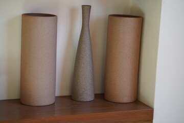 Minimalist ceramic vases in natural tones arranged on a wooden shelf, showcasing simple shapes and textures for stylish home decor accents