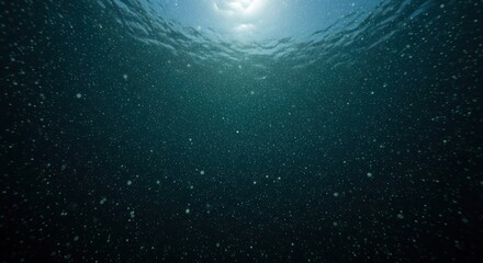 Deep blue ocean water with bubbles rising to the sunlit surface.