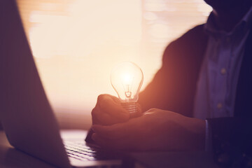 Businessman's hand is choosing light bulb for business creativity plan to goal or creative idea innovation or analyzing marketing data management and target growth or human resources.