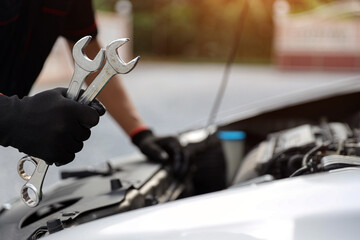 Car mechanic holding wrench for fix service repairing change spare part engine problem or insurance support or range of car check or training workshop and auto care maintenance servicing concepts.