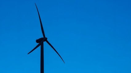 Dynamic wind turbine silhouette against a vibrant azure sky, symbolizing clean energy generation and sustainable future