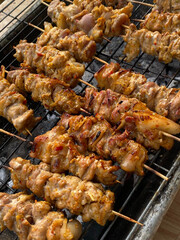 Charred skewers release smoky aroma over grill.