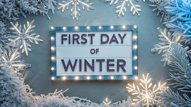 Illuminated first day of winter sign surrounded by frosted evergreen branches and sparkling snowflakes