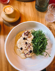 Delicious plate of food featuring fresh herbs and creamy sauce served on a wooden table