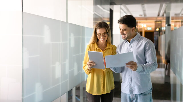 Two positive diverse business professionals discussing electronic and paper reports - Powered by Adobe