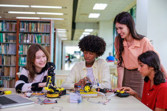 A group of diverse students works with a robotic arm alongside their teacher, showcasing hands-on STEM learning, teamwork, and modern classroom technology.