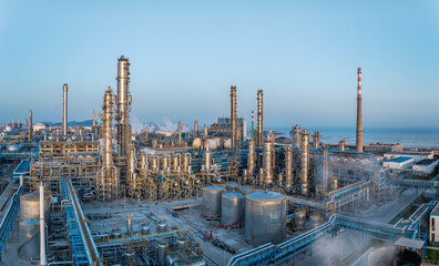 Obraz premium Modern oil refinery industrial plant with pipelines and towers under blue sky.