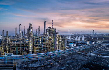Panoramic view of chemical plant construction site with wind turbines at beautiful sunset.