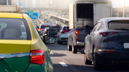 Rear side of taxi sedan car yellow mix green color with turn on brake light. Traffic congestion on the expressway at day time. Heavy traffic conditions in Bangkok Thailand.