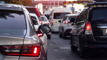 Rear side of luxury bronze car driving on the road. With turn on brake light. Traffic jam on the road with many car at day time. Blurred of many car with town.
