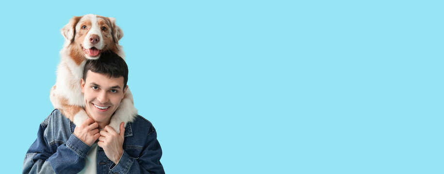 Fototapeta Young man with Australian Shepherd dog hugging on blue background, closeup