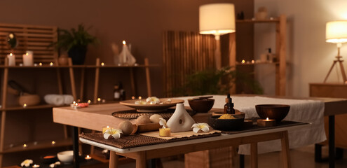 Spa composition with burning candles on table in dark salon