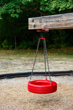 Outdoor children&rsquo;s playground with new red tire swings hanging from wood supports, fun paly in the park
