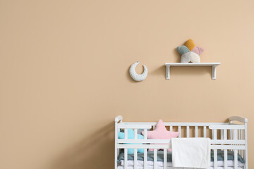 Interior of children's room with crib near beige wall