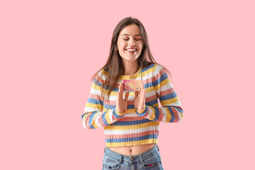 Young woman with credit card on pink background