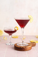 Glasses of Cosmopolitan cocktail with lemon on pink tile table