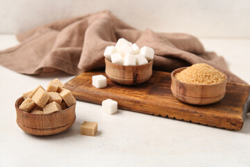 Bowls with different types of sugar on white background