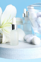 Board with cosmetic products, cotton balls and lily flower on color background, closeup