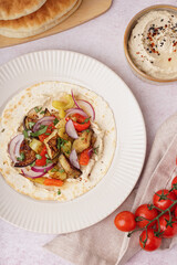 Plate of tasty pita bread with grilled vegetables and hummus on white background