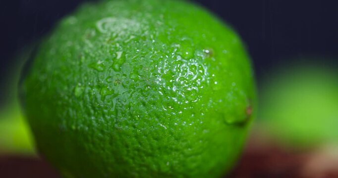 wet green ripe citrus limes scattered on the wooden table in the kitchen, ripe and juicy lime fruits for cooking, green limes with drops of water