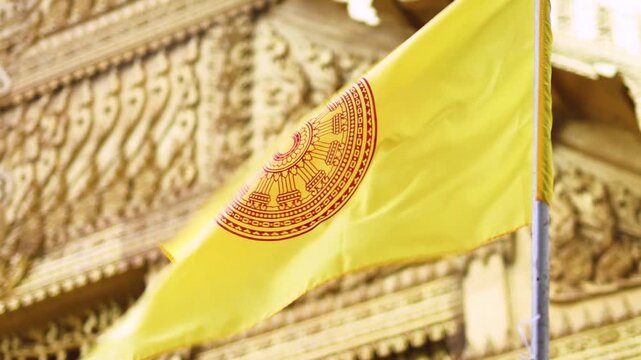 Buddhist flag waving in front of ornate temple architecture, Yellow Buddhist flag with a Dharmachakra symbol waving in the wind, set against detailed golden temple architecture in the background
