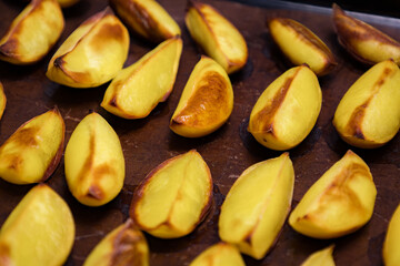 Obraz premium Golden roasted potatoes arranged neatly on a baking tray, showcasing a deliciously crispy texture and inviting aroma during a cooking session