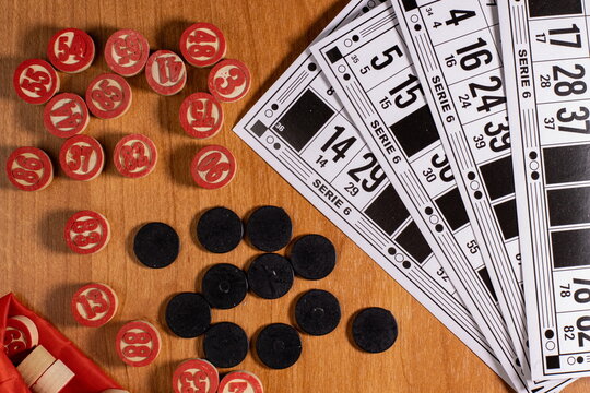 Colorful bingo chips and cards spread on a wooden table during a lively game night with friends or family in a cozy living room setting - Powered by Adobe