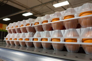 Fresh eggs neatly arranged on a supermarket shelf, showcasing vibrant orange yolks under bright...