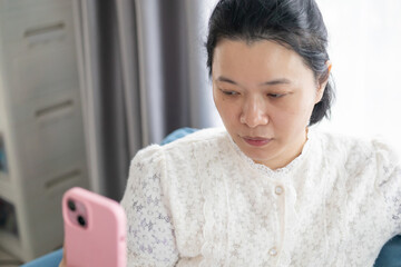 Closeup of an Asian woman concentrating intensely while looking down and interacting with the...