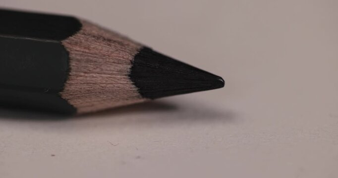 a row of black wooden pencils folded on cheap loose paper, pencils with graphite lead for drawing or other work