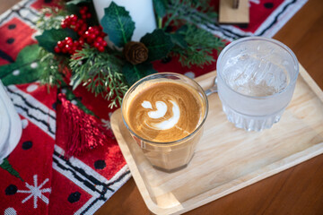 Close up of Hot coffee latte with latte art milk foam in cup mug with Xmas decors and Xmas tree baubles on wood desk Celebrating Merry Christmas and New year,Merry x-mas