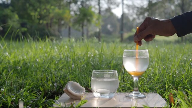 Coconut perfume water mixed with wild honey in a glass on a wooden floor in the grass.