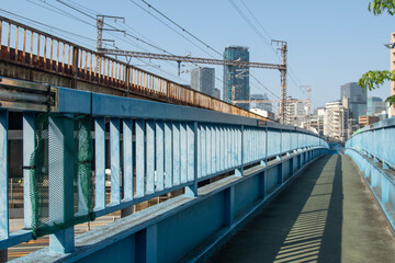都会の高架鉄道と青い歩道橋の近未来的な風景