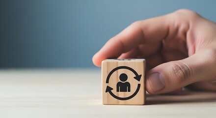 Hand holding wooden block with rotating person icon symbolizing employee turnover talent management or career change concept